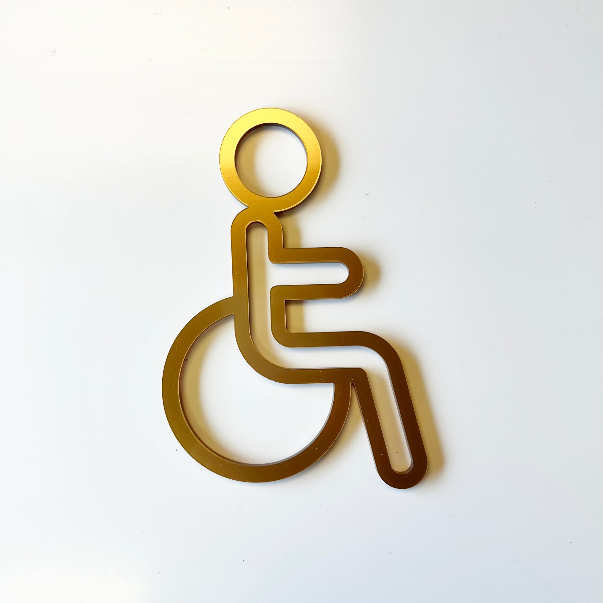 Gold-colored wheelchair accessibility symbol on a white background