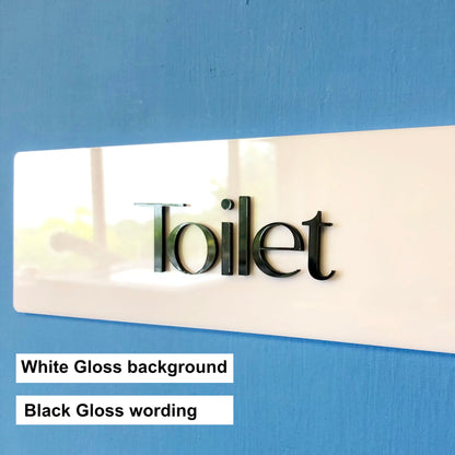 White sign with black 'Toilet' text on a blue background