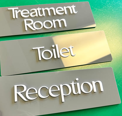 Acrylic nameplates labeled 'Treatment Room', 'Toilet', and 'Reception' on a green gradient background.