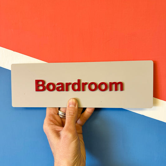 Hand holding a sign with 'Boardroom' text against a colorful background