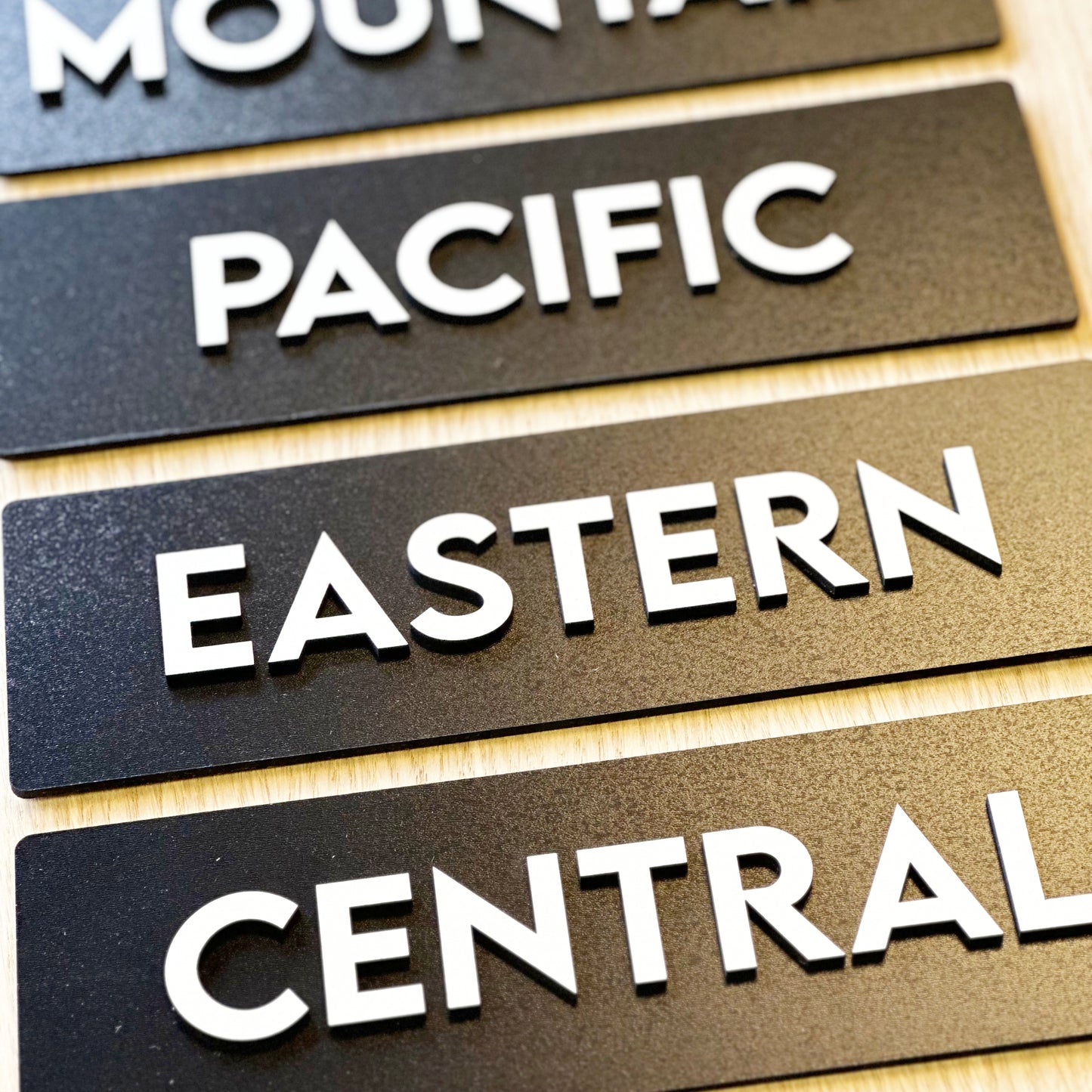 Wooden signs with 'PACIFIC', 'EASTERN', and 'CENTRAL' text on a wooden surface.