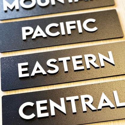 Wooden signs with 'PACIFIC', 'EASTERN', and 'CENTRAL' text on a wooden surface.
