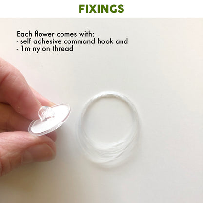 Hand holding a self-adhesive command hook with text about flower fixings on a white background.