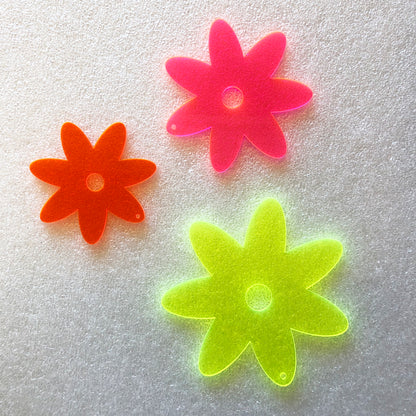 Three colorful flower-shaped objects on a textured white background