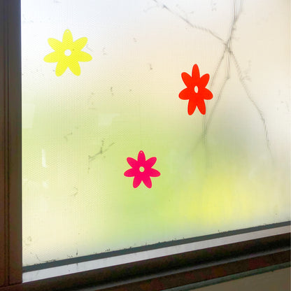 Flower-shaped acrylic ornaments on a glass surface with a blurred background
