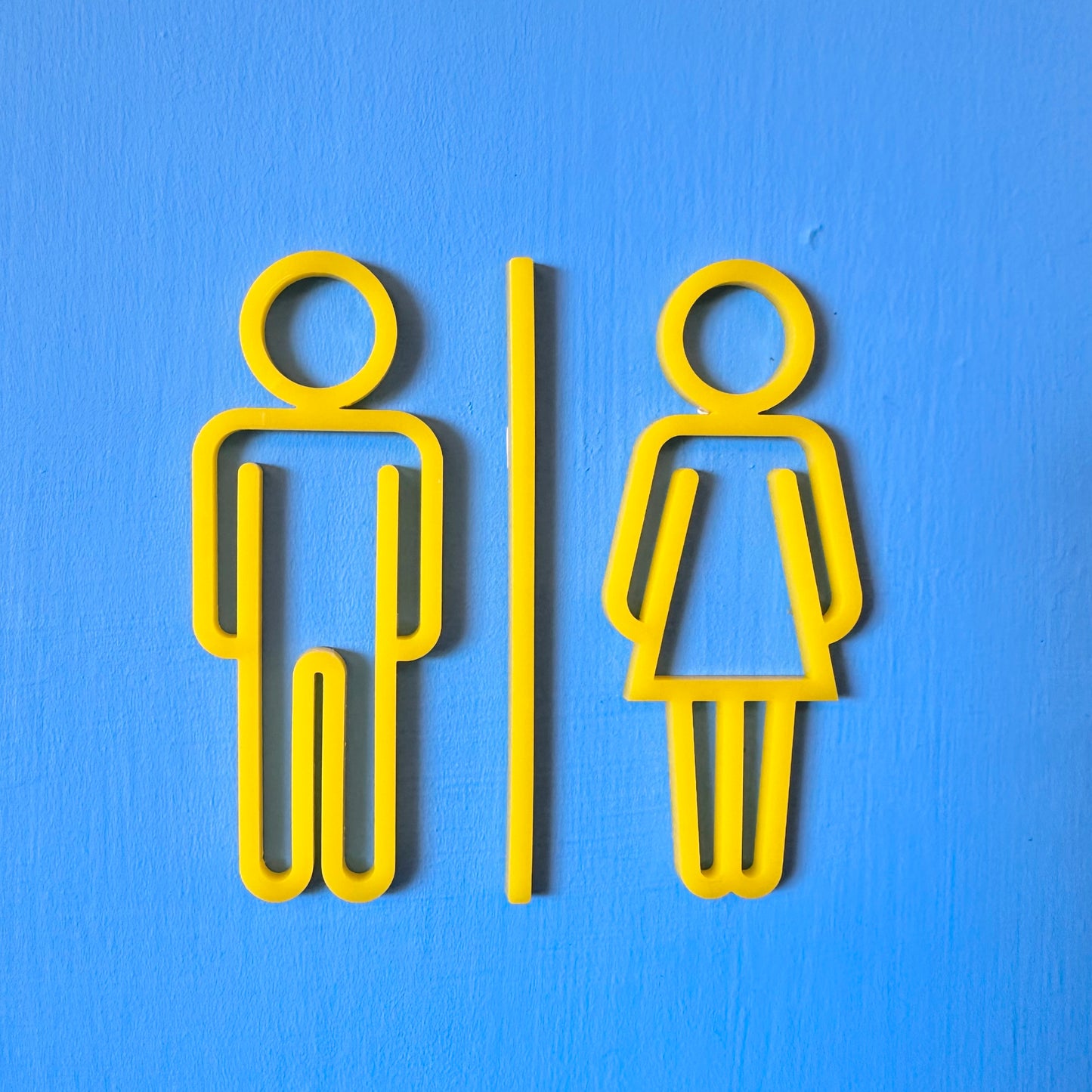 Yellow male and female restroom signs on a blue background