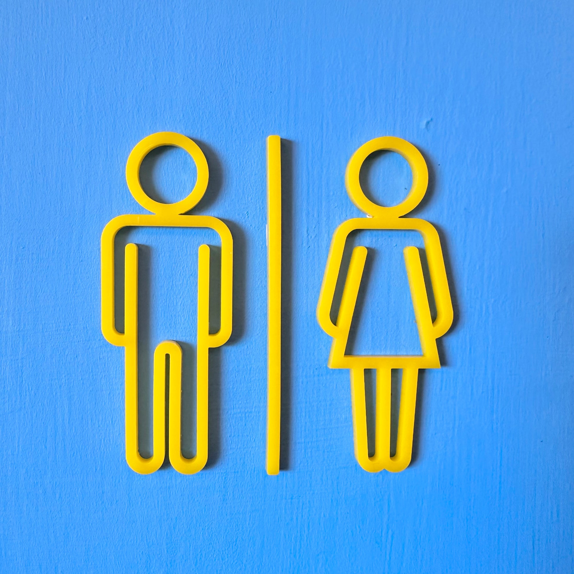 Yellow male and female restroom signs on a blue background