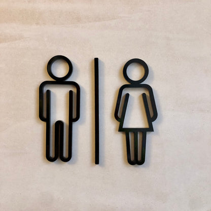 A black acrylic bathroom door sign with a minimalist design featuring silhouettes of a man and a woman.