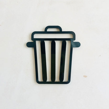 A minimalistic door sign in the shape of a bin, designed in black colour with striped pattern.