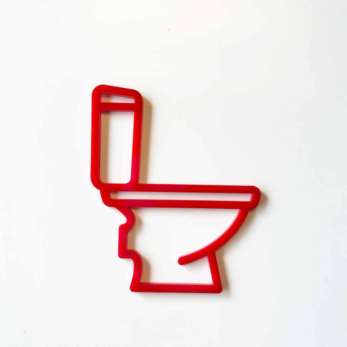 Red toilet-shaped cookie cutter on a white background