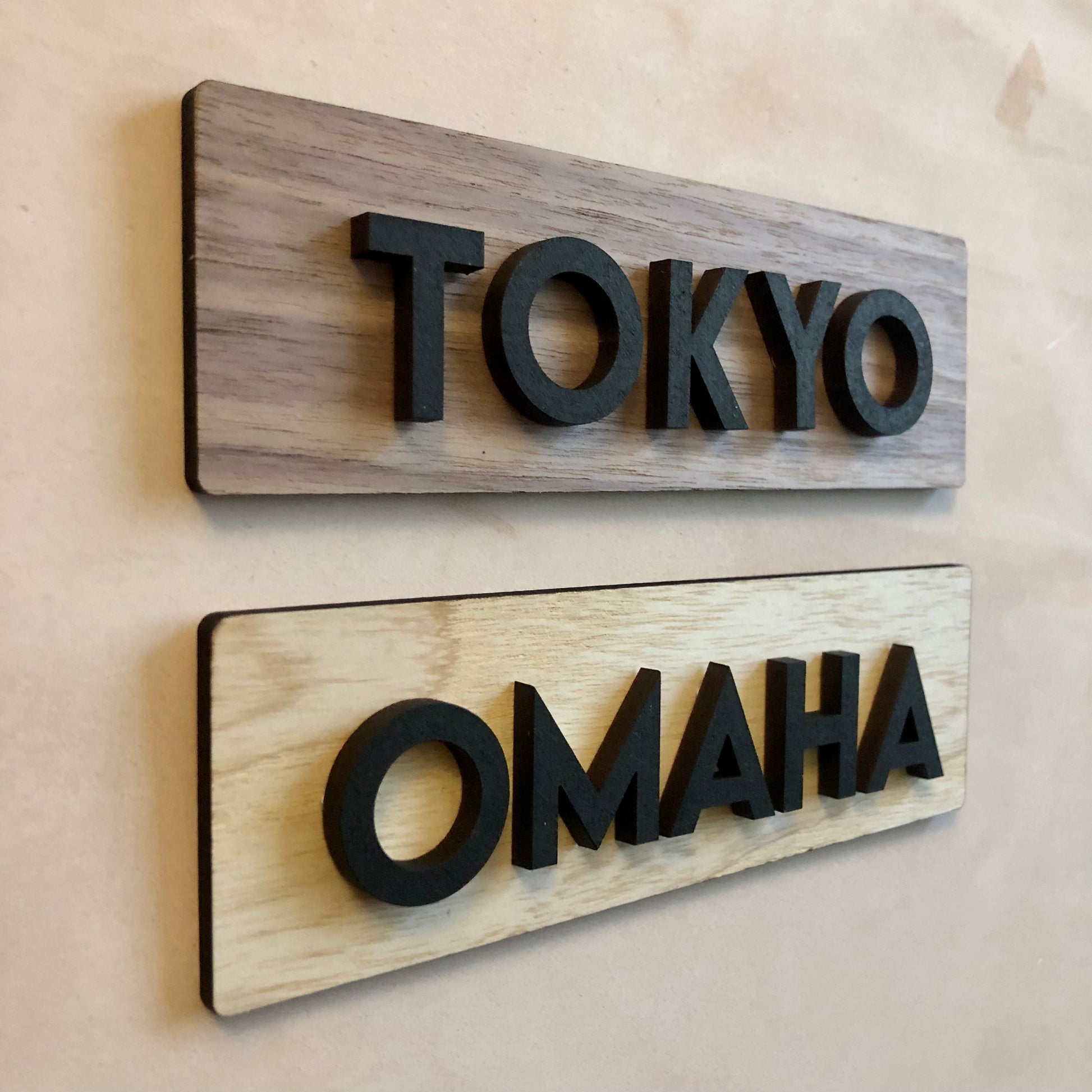 Wooden signs with 'TOKYO' and 'OMAHA' on a beige wall.