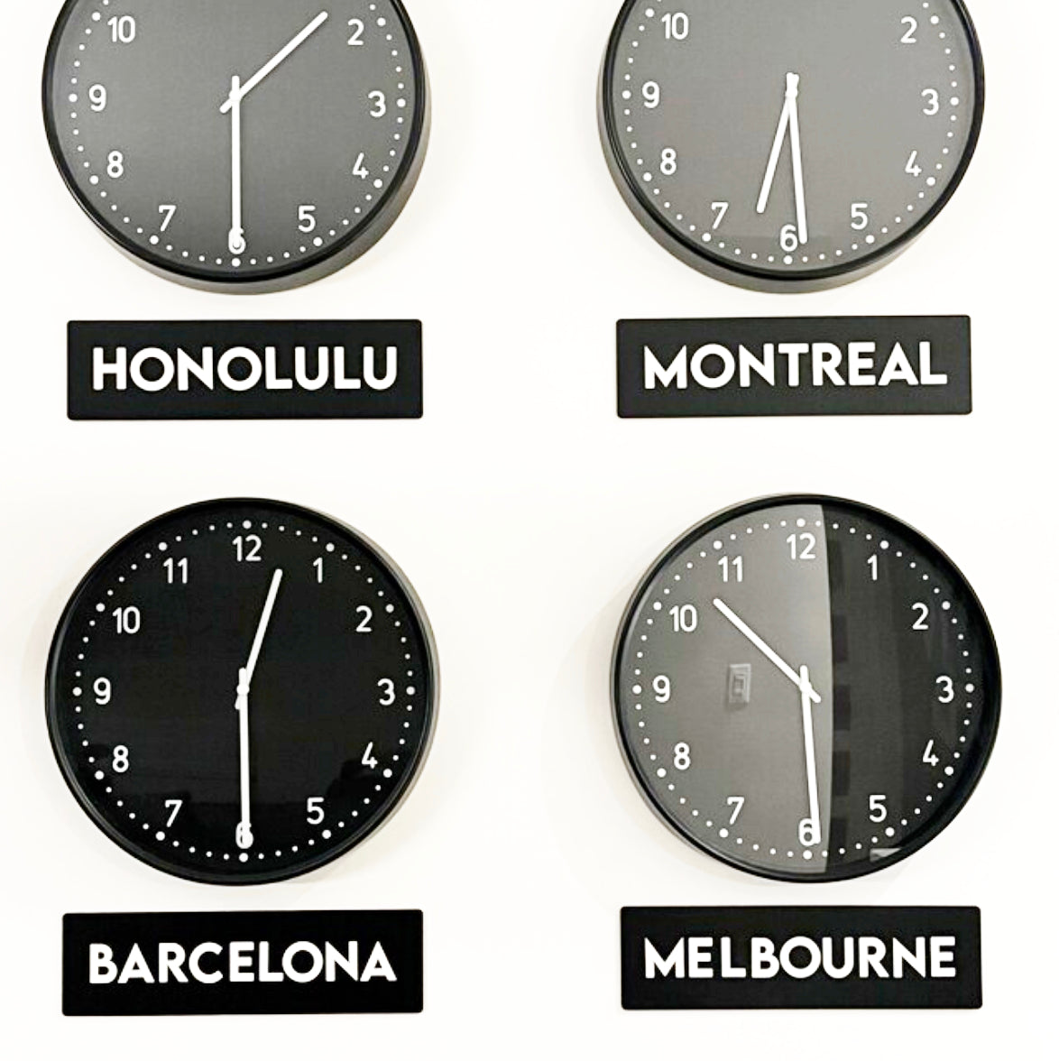 Four wall clocks showing different times with labeled cities on a white background